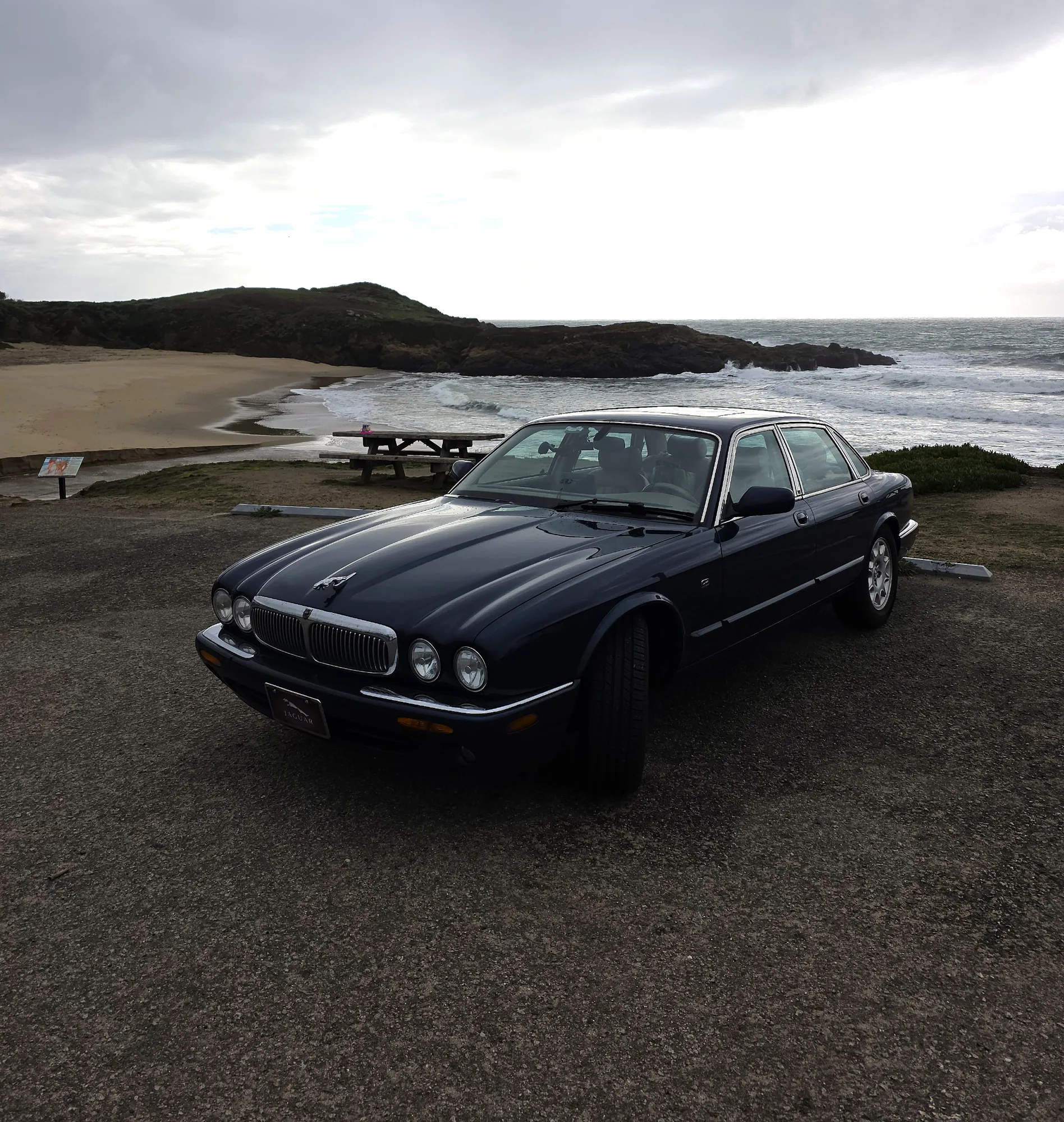 Sapphire Blue Jaguar X308 beside the stormy Pacific coast